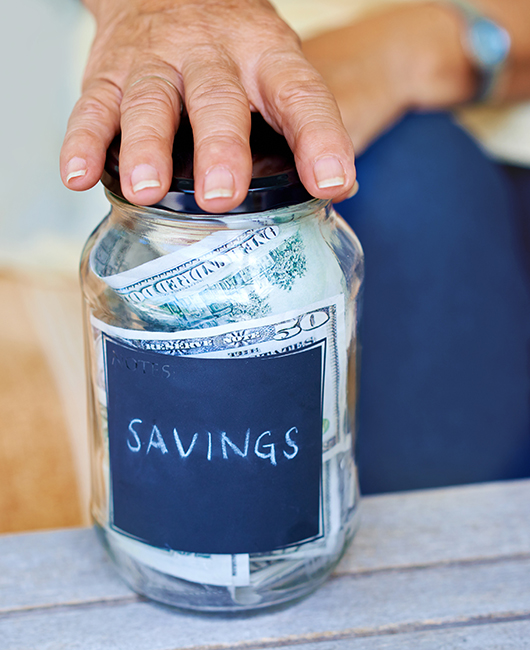 glassx jar with savings written on it with a hand on top.